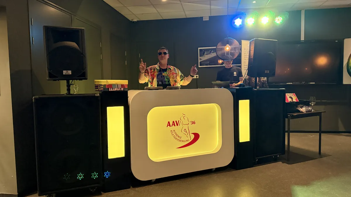 Op maat gebrande DJ-booth met verlichte panelen en bedrijfslogo tijdens een bedrijfsfeest