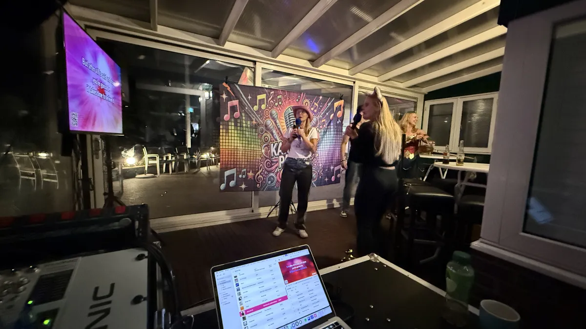 Zangers voor het grote karaokescherm terwijl de host van O-Ke Entertainment de avond begeleidt
