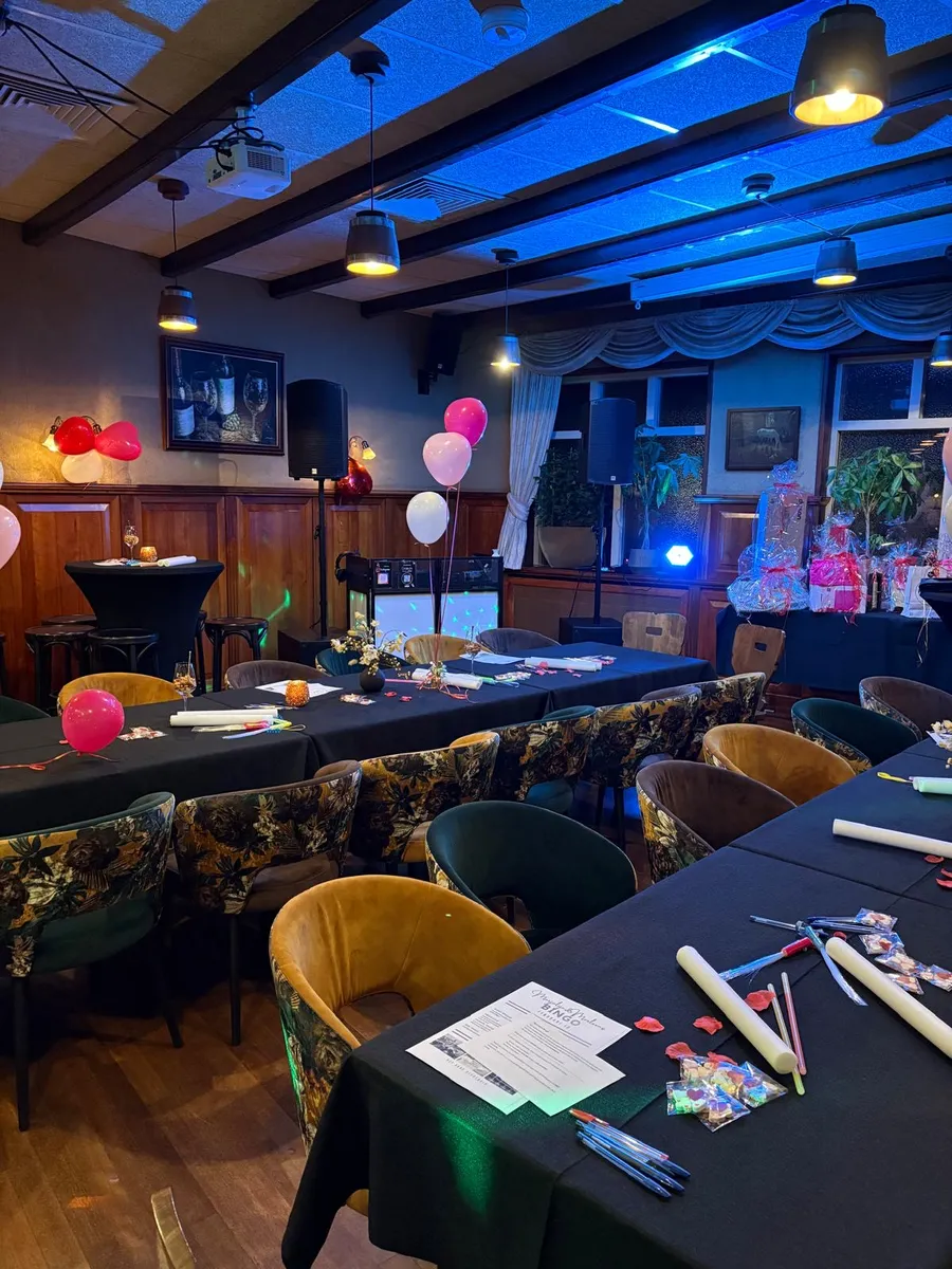 Feestzaal klaargezet voor Swingo met bingokaarten, stiften en ballonnen op de tafels